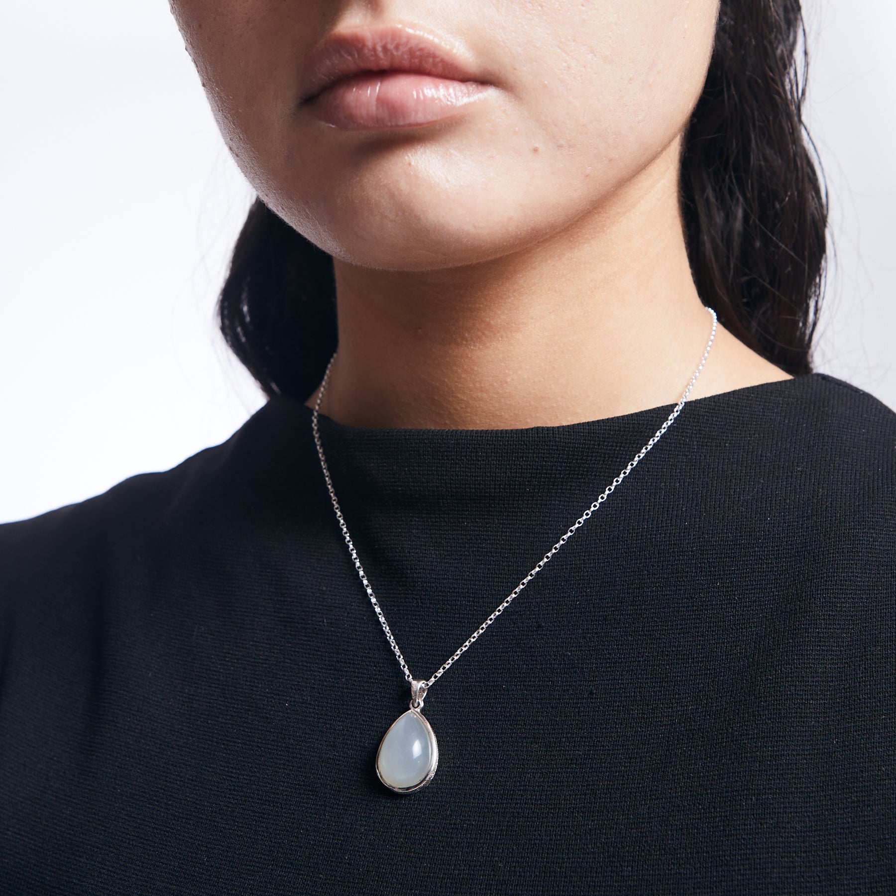 White moonstone teardrop with hammered detailed bezel with sterling silver chain on model