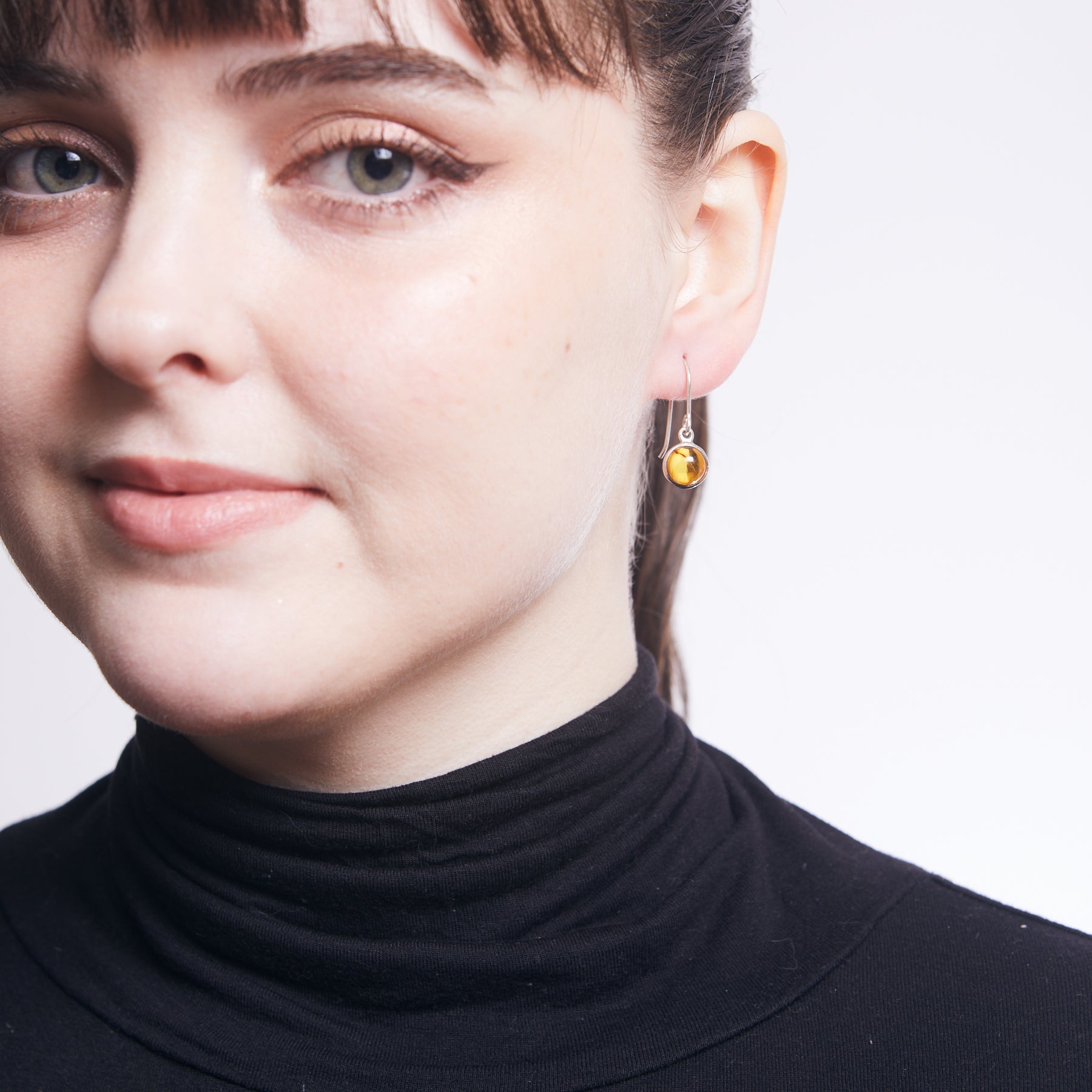 Amber cabochon round bezel drop earrings on model