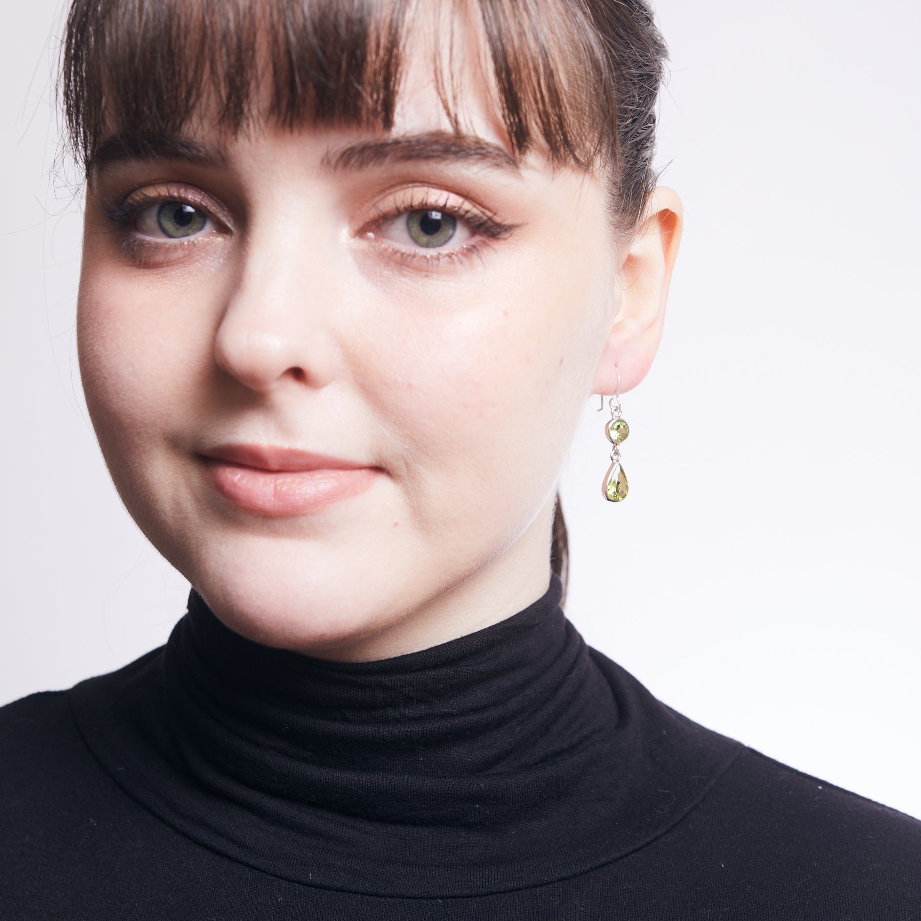 Peridot faceted oval and teardrop drop earrings on model