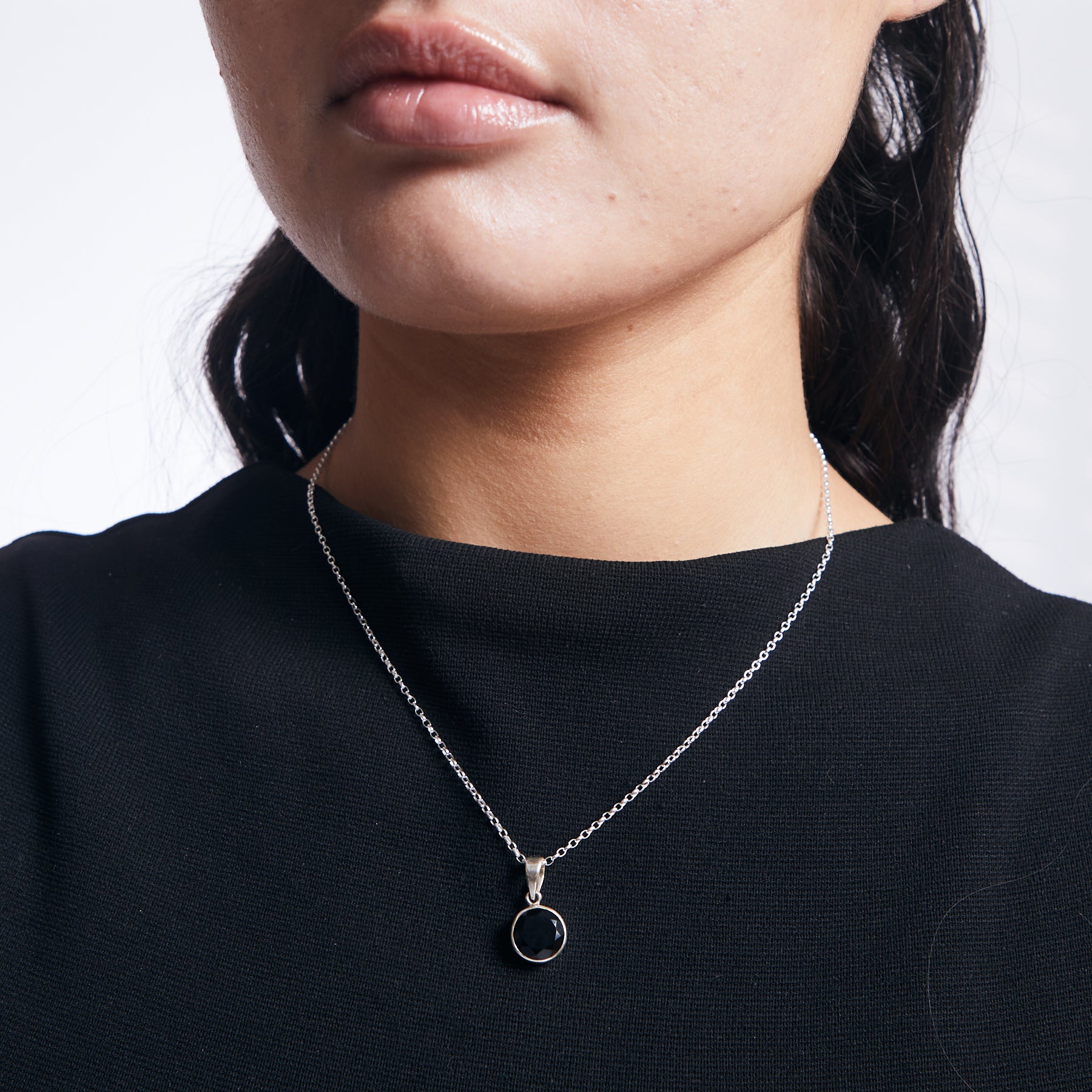 Black onyx pendant with faceted finish and sterling silver chain on model