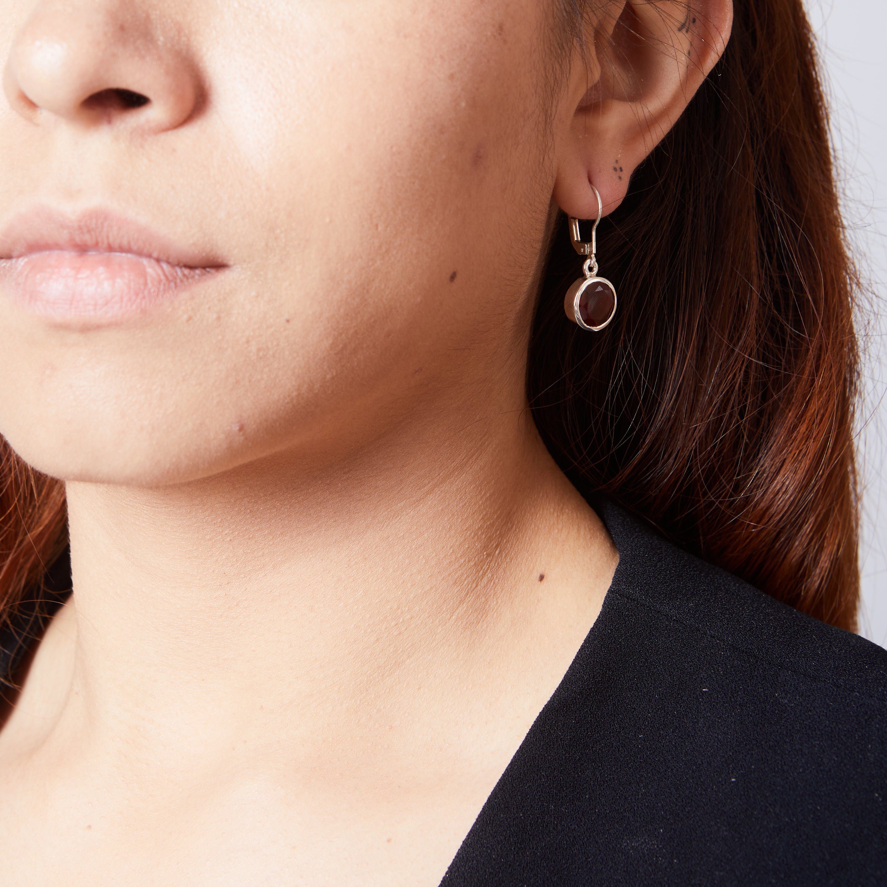 Garnet faceted round bezel set clasp drop earrings on model